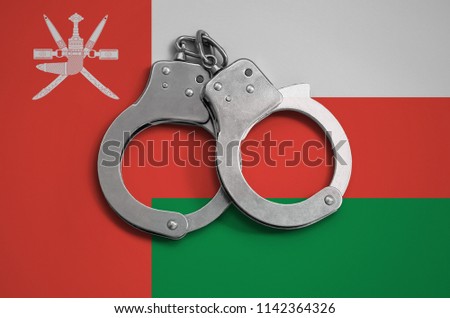 Oman flag  and police handcuffs. The concept of observance of the law in the country and protection from crime