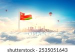 Oman national flag blowing in beautiful clouds with modern skyline buildings. The flag with hot air balloon in the sky. Oman national flag for independence day.