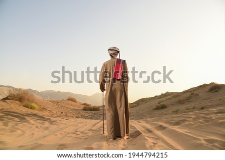 Omani guy standing in Arabian desert watching the horizon