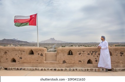 omani man in traditional outfit ilooking at the landscape of remote countryside