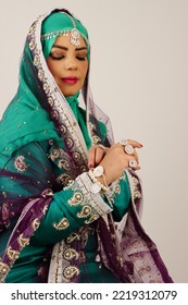 Omani woman wearing traditional clothes and jewelry looking at hand  - Shutterstock ID 2219312079
