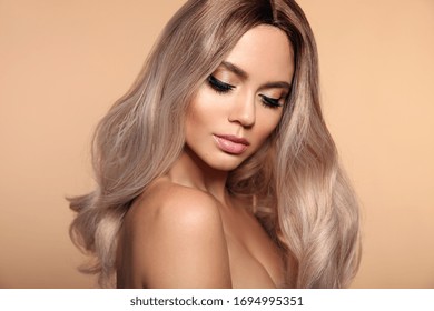 Ombre Blond Wavy Hairstyle. Beauty Fashion Blonde Woman Portrait. Beautiful Girl Model With Makeup, Long Healthy Hair Style Posing Isolated On Studio Beige Background.