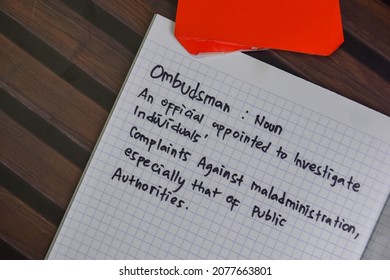 Ombudsman write on a book isolated on Wooden Table.