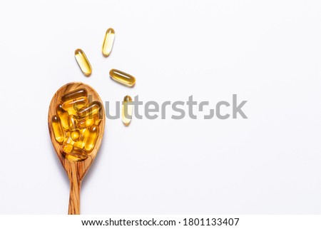 Omega 3 cod liver oil capsules in the wooden spoon on white background with copy space for your design. immunity support capsules. Health care concept.
