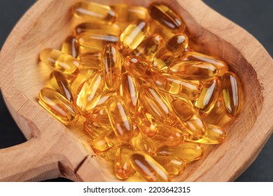 Omega 3 Fish Oil Gold Capsules In Wooden Rustic Bowl Close Up