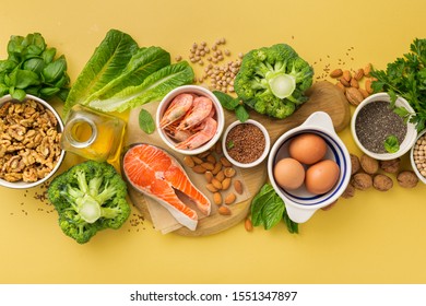 Omega 3 Food Sources And Omega 6 On Yellow Background Top View. Foods High In Fatty Acids Including Vegetables, Seafood, Nut And Seeds