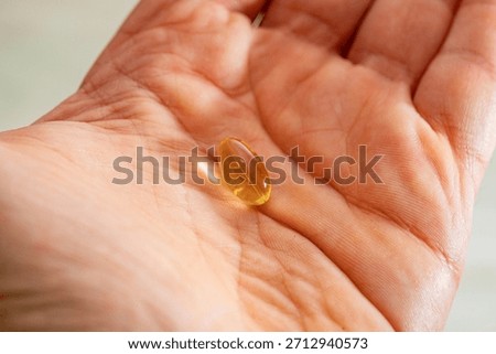 Omega 3 translucent capsule tablet over human hand palm, white person.
