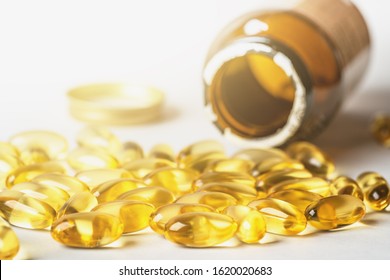 Omega 3 Yellow Capsules And Pill Bottle On White Background. EPA And DHA Are Two Types Of Omega-3 Fats Essential Fatty Acids For Healthy Living.