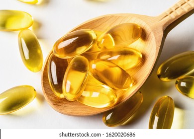 Omega 3 Yellow Capsules In Wooden Spoon On White Background. EPA And DHA Are Two Types Of Omega-3 Fats Essential Fatty Acids.