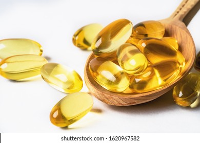 Omega 3 Yellow Capsules In Wooden Spoon On White Background. EPA And DHA Are Two Types Of Omega-3 Fats Essential Fatty Acids.