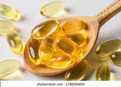 Omega 3 Yellow Capsules In Wooden Spoon On White Background. EPA And DHA Are Two Types Of Omega-3 Fats Essential Fatty Acids.