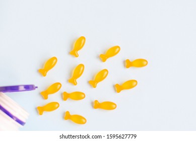 Omega Vitamins For Children In The Form Of Fish On A Blue Background. Useful Supplements For Children.