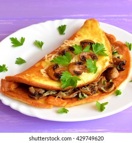 Omelet With Fried Mushrooms, Cheese And Fresh Parsley. Yummy Veggie Omelet On A Plate And Purple Wooden Background. Egg Omelette Vegetarian Recipe. Homemade Organic Vegetarian Food For Breakfast.