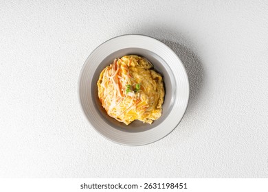 Plato de arroz de tortilla con huevos esponjosos y relleno, cuidadosamente plateado en un plato de cerámica blanca minimalista.