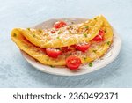 An omelet with tomato and parsley, eggs for breakfast, a healthy vegetarian omelette with cheese, on a slate background