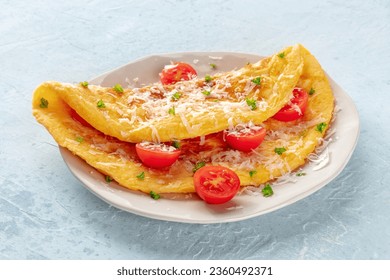 An omelet with tomato and parsley, eggs for breakfast, a healthy vegetarian omelette with cheese, on a slate background