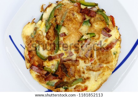 Omelete with green pepper, red pepper and bacon, on blue striped pranche dish