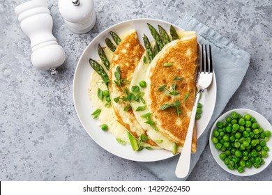 omelette with asparagus and green peas on white plate, top view, grey background,