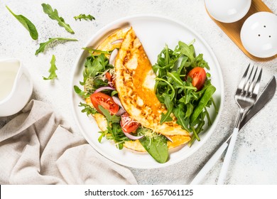 Omelette With Fresh Salad Leaves And Tomato On White Plate. Top View.