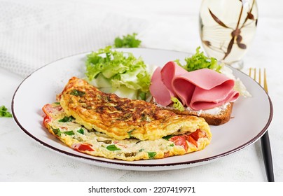 Omelette With Tomatoes, Cheese, Green Onion And Sandwich With Ham On White Plate.  Frittata - Italian Omelet.