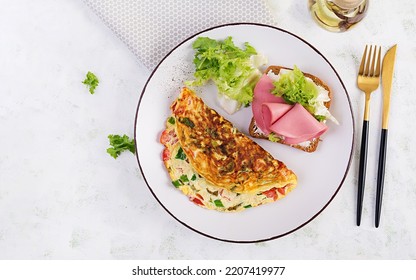 Omelette With Tomatoes, Cheese, Green Onion And Sandwich With Ham On White Plate.  Frittata - Italian Omelet. Top View