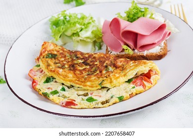 Omelette With Tomatoes, Cheese, Green Onion And Sandwich With Ham On White Plate.  Frittata - Italian Omelet.