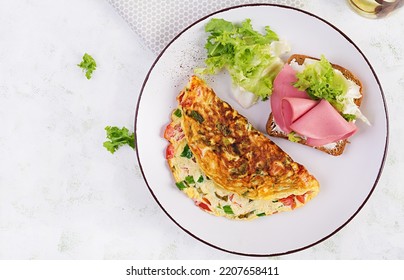 Omelette With Tomatoes, Cheese, Green Onion And Sandwich With Ham On White Plate.  Frittata - Italian Omelet. Top View