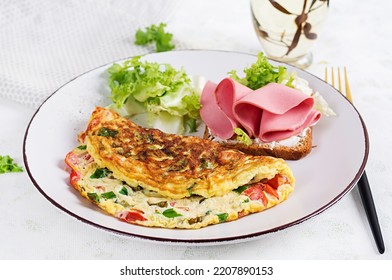 Omelette With Tomatoes, Cheese, Green Onion And Sandwich With Ham On White Plate.  Frittata - Italian Omelet.