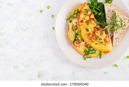 Omelette With Tomatoes, Ham, Cheese And Green Herbs On Plate.  Frittata - Italian Omelet. Top View, Overhead, Copy Space