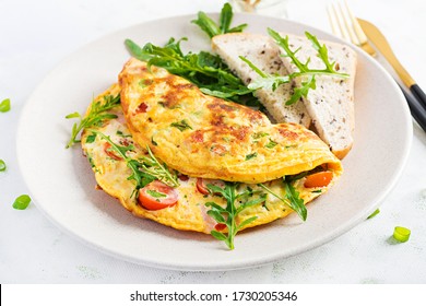 Omelette With Tomatoes, Ham, Cheese And Green Herbs On Plate.  Frittata - Italian Omelet.