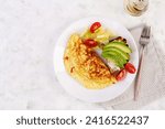 Omelette with tomatoes and toast with avocado on white plate.  Frittata - italian omelet. Top view, flat lay