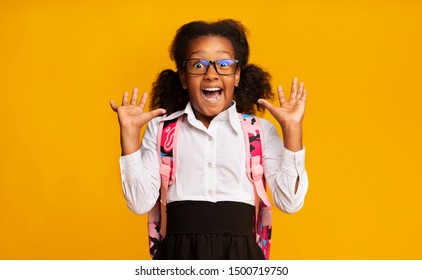 Omg, Back To School. African American Elementary School Girl Shouting In Surprise Over Yellow Studio Background. Empty Space