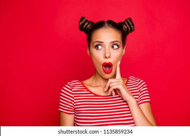 OMG! Close up face of shocked astonished girl with modern hairdo having wide open mouth and brown eyes looking at camera and to touch her cheek by finger isolated on red background with copyspace