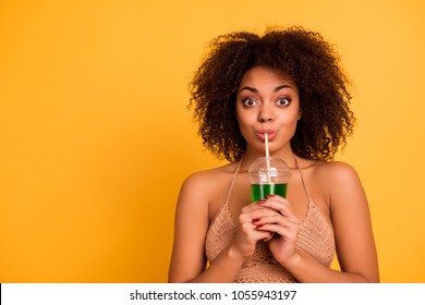 OMG! So delicious! Funny cute attractive careless mixed-race woman is drinking green alcohol cocktail is a plastic cup using a straw, isolated on bright vivid background, copy space