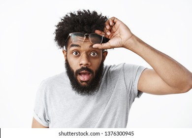 Omg unbelievable. Portrait of impressed and surprised handsome adult african american bearded guy taking off glasses cannot believe own eyes dropping jaw and bending towards camera amazed