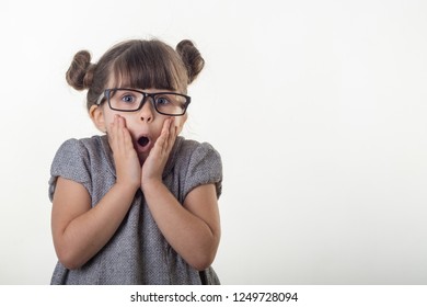 OMG! Wow! Happy Surprised Child 4-5 Years Old Girl Wearing Eyeglasses, Screaming With Open Mouth And Crazy Expression, Isolated On White. Shocked Face Little Kid Girl On White Background.  