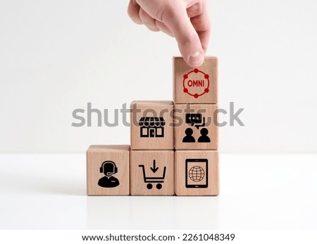 Omni Channel marketing concept. Digital online marketing. Hand places wooden cube with omni text on wooden cubes with marketing symbols.