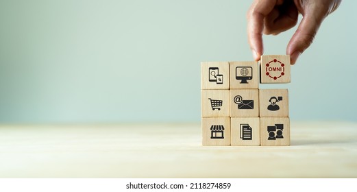 Omnichannel marketing concept. Digital online marketing commerce sale. For customer engagement by integrated online and offline channels. Hand holds wooden cube with omni text standing with omni icon