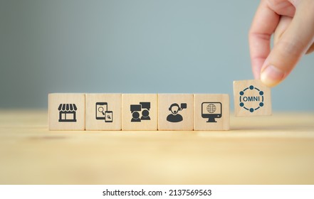 Omnichannel Marketing Concept. Digital Online Marketing Commerce Sale. Customer Engagement Integrated Online And Offline Channels. Hand Holds Flat Wooden Cube With Omni Text Standing With Omni Icons.