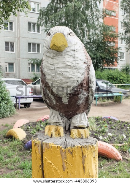 Omsk, Russia -\
June 27, 2016: Sculpture made of wood falcon sitting on a tree\
stump in one of the children\'s\
courts