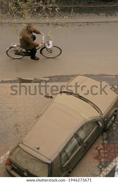 On April 17,\
2006, Beijing ushered in a sandstorm. The picture shows a dusty car\
and people passing by by\
bike.