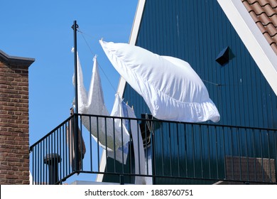 On A Balcony Of A Blue House, A Clothesline With Clothes And Sheets Hangs To Dry In The Wind.