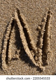 On The Beach In The Sand Is Carved The Letter N