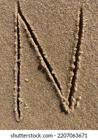 On The Beach In The Sand Is Carved The Letter N