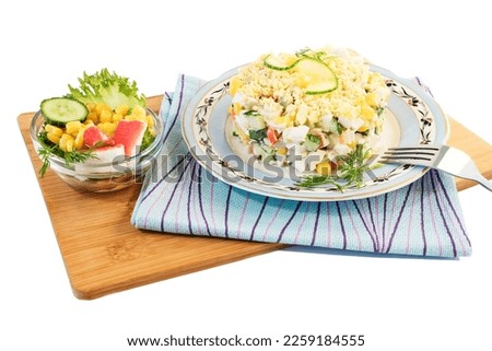 On a beautiful dish, fresh vegetable salad with crab sticks, sweet corn, cheese,fresh cucumber, boiled eggs, dill, mayonnaise.