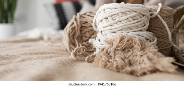 on the bed are two macrame rope skewers. Weaving macrame. Accessories in the form of macrame twine are lying on the bed. Baner copy space