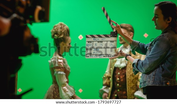 On Big Film Studio Professional Crew Shooting\
Period Costume Drama Movie. On Set: Camera Assistant Using\
Clapperboard, Cameraman Shooting Green Screen Scene with Two Actors\
in Renaissance Clothes