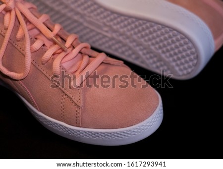 On black background pale pink womens sports sneakers with white sole. Street style and fashion. Advertizing of footwear.