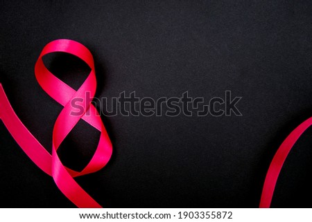 On a black background, a pink satin ribbon in the form of the number eight. Gift wrap. The concept of March 8 and Valentine's Day.A greeting card.