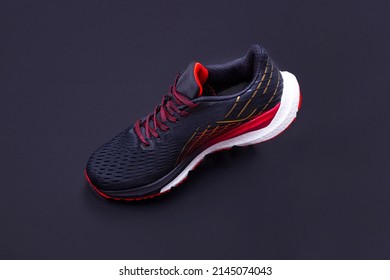 On A Black Background, A Black And Red Sneaker In Limbo. Sport Shoes. Sport And Healthy Lifestyle Concept